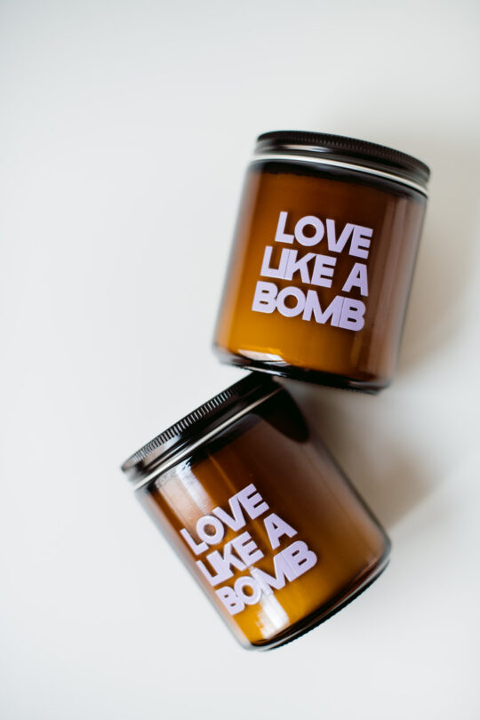 Candela profumata all'oud Love Like a Bomb, La Calathea, in vasetto di vetro scuro e packaging bordeaux e viola